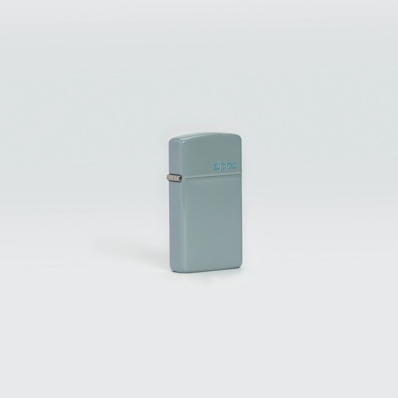 Lifestyle image of Zippo Slim Flat Grey Zippo Logo Pocket Lighter standing in a grey scene.