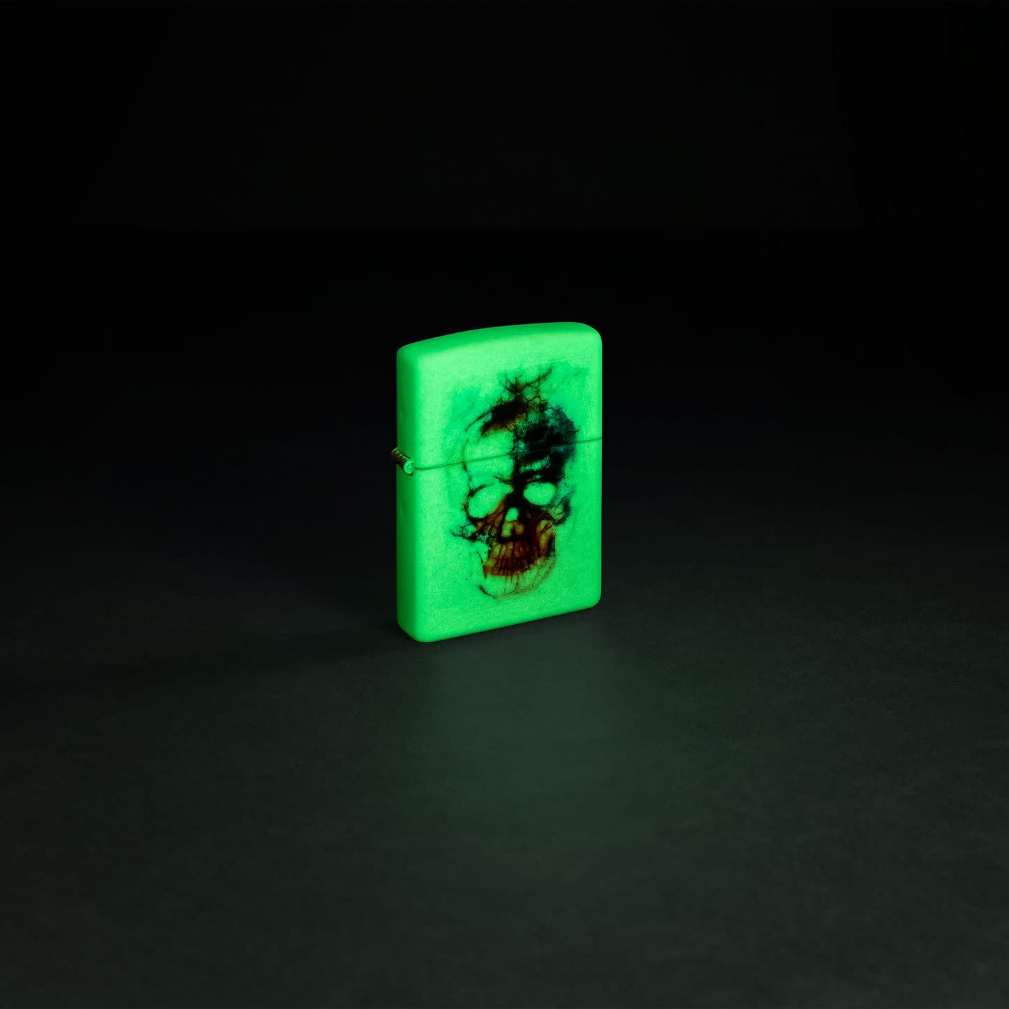 Glamour shot of  Zippo Skull Print Design Glow in the Dark Matte Windproof Lighter glowing in the dark.