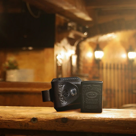 Lifestyle image of Jack Daniel's Black Matte Windproof Lighter and pouch standing on a bar.