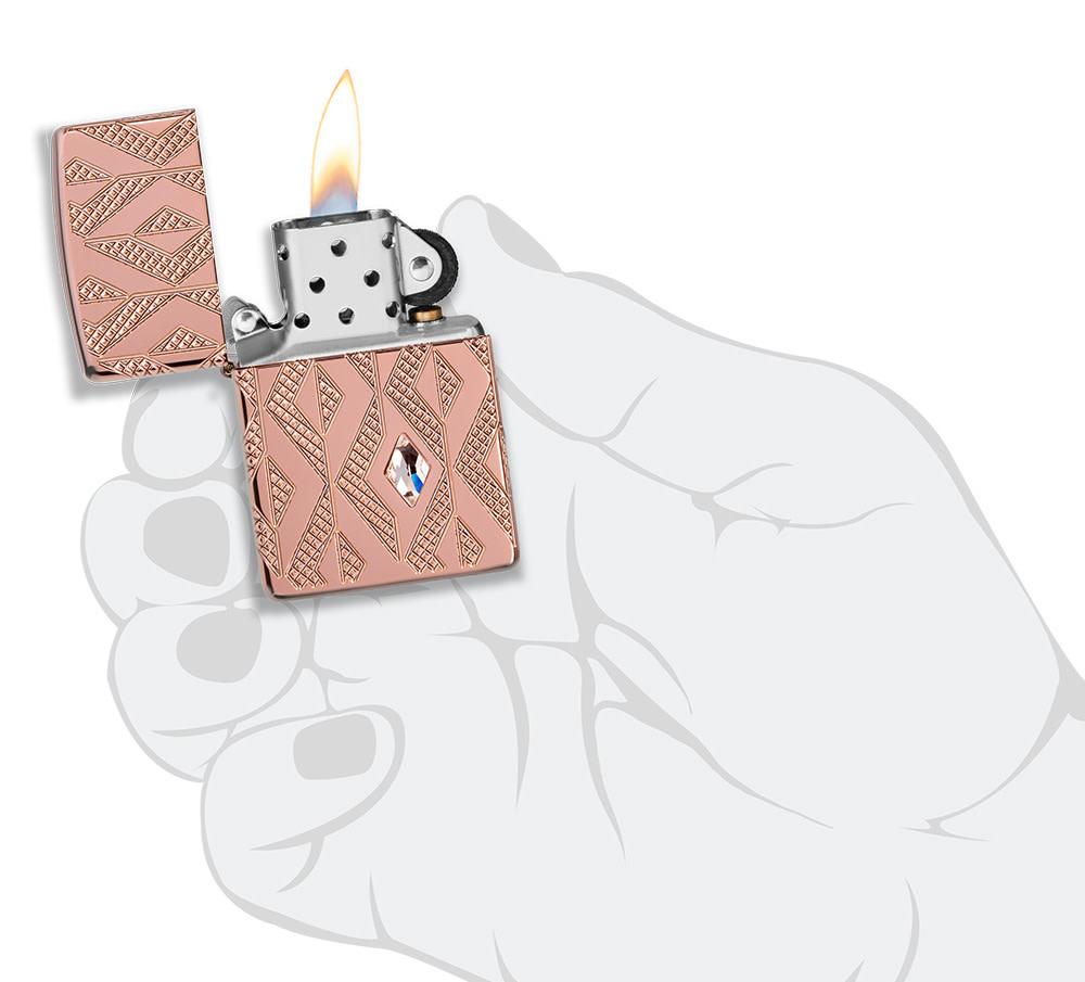 Geometric Diamond Pattern Design Armor® Rose Gold Windproof Lighter lit in hand.